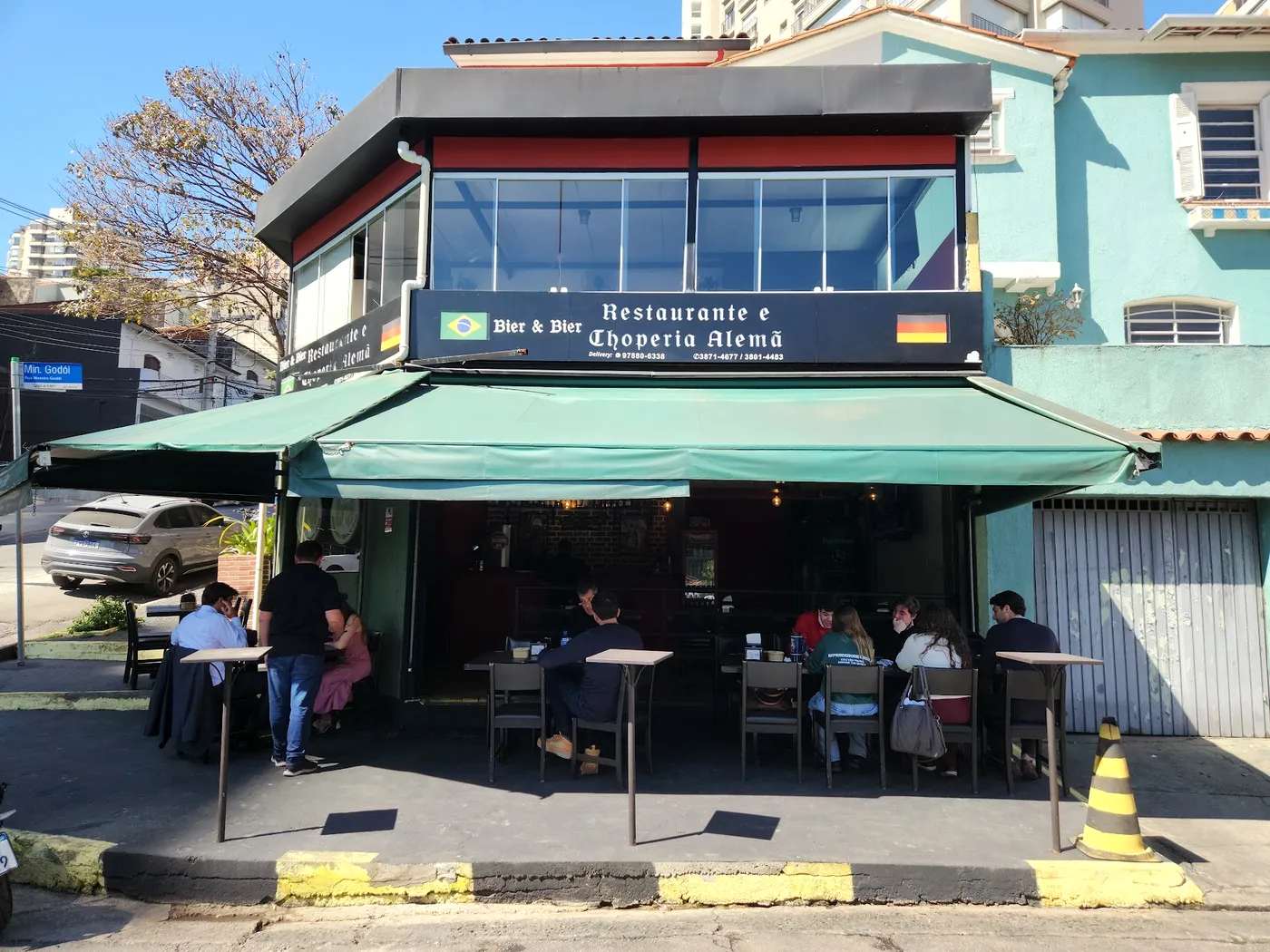 Fachada do Bier & Bier na esquina, com toldo verde e mesas na calçada