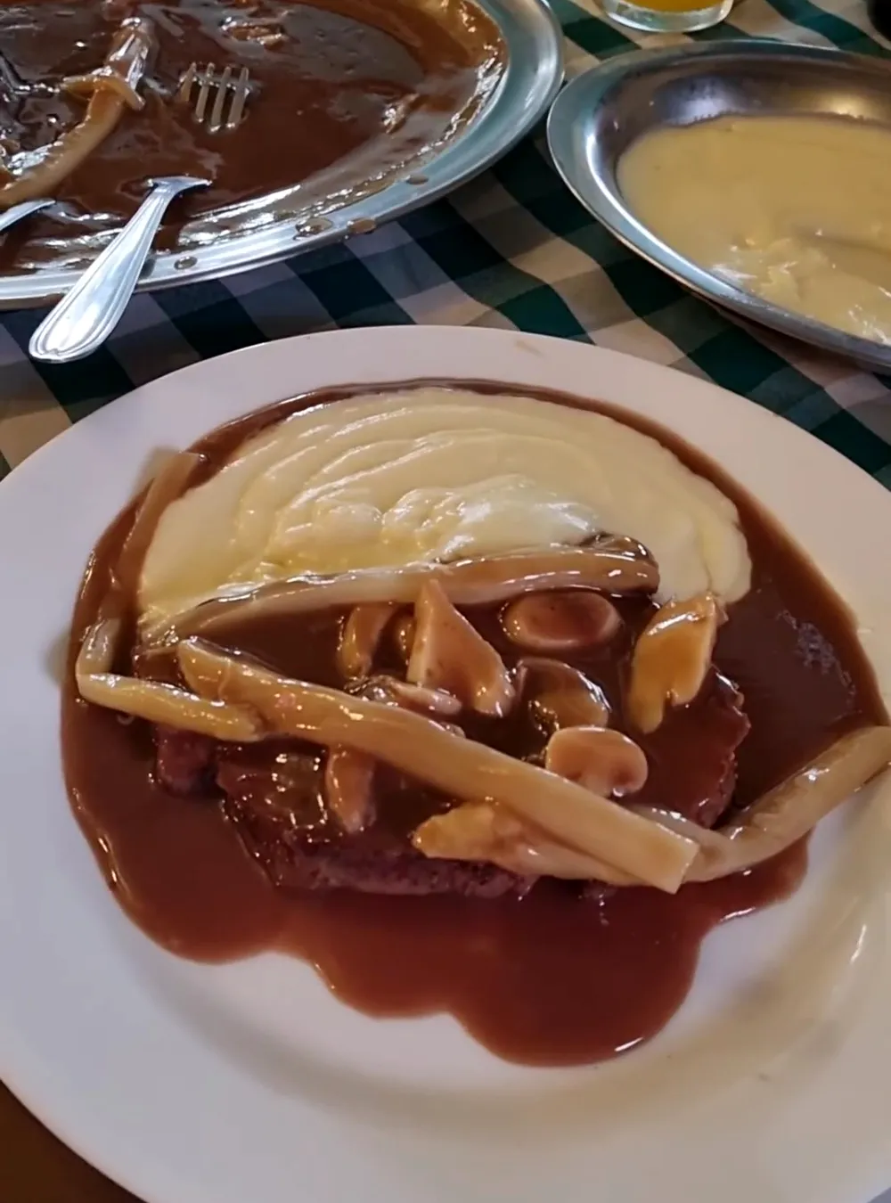 Prato com molho escuro, cogumelos e batata palha